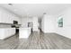 Open floor plan featuring kitchen with white cabinets, stainless appliances, and wood-look flooring at 809 Benoi Dr, Davenport, FL 33896