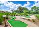 Well-maintained putting green area with diverse hole designs, surrounded by lush landscaping and palm trees at 809 Benoi Dr, Davenport, FL 33896