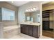 Bright bathroom featuring a soaking tub, vanity with stone counters, and an entrance to the walk-in closet at 8491 Pippen Dr, Orlando, FL 32836