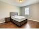 A bedroom with a wooden frame bed, bedside table, and wooden floors, with a window providing natural light at 8491 Pippen Dr, Orlando, FL 32836