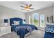 Cozy bedroom featuring bright blue bedding, a ceiling fan and a large window offering natural light at 8500 Iron Mountain Trl, Windermere, FL 34786