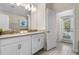 Bright bathroom featuring double sinks, white cabinets, neutral walls, and a door to the outdoor area at 8807 Interlocking Ct, Davenport, FL 33896