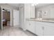 Bathroom with a double sink vanity, white cabinets, granite countertops, and an open door to another bedroom at 8807 Interlocking Ct, Davenport, FL 33896