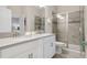 Modern bathroom with a double sink vanity, white cabinets, granite countertops, and a glass shower at 8807 Interlocking Ct, Davenport, FL 33896