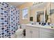 Bright bathroom featuring a vanity with a white cabinet, a large mirror, and a toilet with a polka dot shower curtain at 9141 Camden Gardens St, Orlando, FL 32827