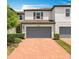 Two-story home featuring a brick driveway, gray two-car garage and well-maintained landscaping at 1045 Desert Candle Dr, Ocoee, FL 34761
