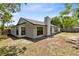 Exterior rear view of a light-colored home with a dark roof and windows, plus a spacious backyard at 12929 Louisiana Woods Ct, Orlando, FL 32824