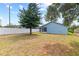 Spacious backyard with a large tree, a white fence, and a blue home with a screened-in porch at 12952 Downstream Cir, Orlando, FL 32828