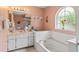Bathroom showcasing tub, vanity, decorative mirror, and natural light window at 12952 Downstream Cir, Orlando, FL 32828
