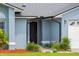 Inviting home entrance featuring a covered porch, black front door, and tidy landscaping at 12952 Downstream Cir, Orlando, FL 32828