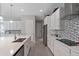 Modern island kitchen featuring white cabinets, stainless steel appliances, and gray backsplash at 14138 Alafaya Oak Bnd, Orlando, FL 32828