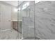 Well lit shower with rain shower head, corner seat, and stylish marble tile walls at 1459 Santorini Way, Tavares, FL 32778
