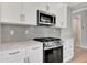 Bright kitchen features modern white cabinets, stainless appliances, granite counters, and a gray backsplash at 1459 Santorini Way, Tavares, FL 32778