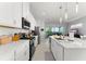 Modern kitchen with white cabinetry, stainless steel appliances, and an island with seating overlooking the living area at 2301 Datura Loop, St Cloud, FL 34772