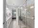 Bright bathroom with double vanity, tiled floor, glass-enclosed shower, and view into bedroom at 2301 Datura Loop, St Cloud, FL 34772