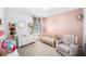 Comfortable Bedroom with plush chair, changing table, crib, neutral carpet, and pink accent wall at 266 Caryota Ct, New Smyrna Beach, FL 32168
