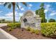 Community entrance sign nestled among lush landscaping with palm trees and shrubbery at 266 Caryota Ct, New Smyrna Beach, FL 32168