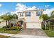 Two-story home featuring stone accents, dark shutters, a paver driveway, and lush landscaping at 266 Caryota Ct, New Smyrna Beach, FL 32168