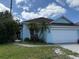 Charming light blue home featuring a white garage door and complemented by palm trees in the front yard at 307 Hollingshead Loop, Davenport, FL 33896