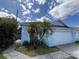 Charming light blue home featuring a white garage door and complemented by palm trees in the front yard at 307 Hollingshead Loop, Davenport, FL 33896