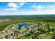 Expansive aerial view of a community centered around a picturesque lake, surrounded by lush greenery and homes at 3078 Mandolin Dr, Kissimmee, FL 34744