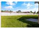 View of a large, grassy backyard with a white fence and neighboring homes at 3078 Mandolin Dr, Kissimmee, FL 34744