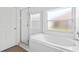 Bright bathroom with white tile, bathtub, glass shower, and frosted window at 3078 Mandolin Dr, Kissimmee, FL 34744
