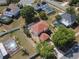 Aerial view of a charming home with a red roof, featuring a screened pool and lush greenery at 3216 White Blossom Ln, Clermont, FL 34711