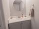 Compact powder room with a white countertop vanity and stylish round mirror at 3216 White Blossom Ln, Clermont, FL 34711
