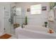 Bathroom featuring a soaking tub, walk-in shower with glass enclosure, and tiled walls at 3755 Sanibel St, Clermont, FL 34711