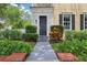 Home showcasing a welcoming front entrance with a black door, well-manicured landscaping and a brick border at 4001 Corrine Dr, Orlando, FL 32814