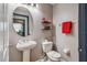 Well-lit half bathroom with a pedestal sink, toilet, and decorative wall shelves at 401 Magpie Ct, Kissimmee, FL 34759