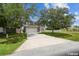 View of the home with a long driveway and large trees in the front yard at 401 Magpie Ct, Kissimmee, FL 34759