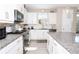Modern kitchen featuring white cabinets, granite countertops, stainless steel appliances, and a stylish backsplash at 406 Alcove Dr, Groveland, FL 34736