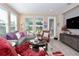 Bright living room featuring a comfortable sectional, large windows, and a stylish entertainment center at 406 Alcove Dr, Groveland, FL 34736