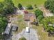 Aerial view of a home with solar panels and multiple outbuildings in a tree-filled, landscaped setting at 4432 Freedom Rd, Kissimmee, FL 34746