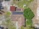 Aerial view of a house featuring a brown roof, solar panels, an outdoor fireplace, and surrounding greenery at 4432 Freedom Rd, Kissimmee, FL 34746