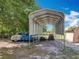 Large metal carport with vehicles, a tractor, and landscaping equipment in the gravel drive at 4432 Freedom Rd, Kissimmee, FL 34746