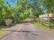 Gravel driveway leading to property with a wooden fence, trees, and an ADT security sign at 4432 Freedom Rd, Kissimmee, FL 34746