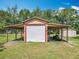 View of garage with a white door and a large covering, plus yard tools and equipment are nearby at 4432 Freedom Rd, Kissimmee, FL 34746
