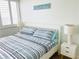 Cozy bedroom with a large window, a comfortable bed with striped bedding and a 