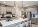 Modern kitchen features gray cabinetry, stainless steel appliances, pendant lighting, and an expansive white countertop island at 560 Southern Edge Way, Sanford, FL 32771