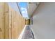 A brick pathway leads along the house, next to a tall wood fence, toward a wooden access gate at 635 Holbrook Cir, Lake Mary, FL 32746