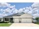 Beautiful single-story home with a manicured lawn, vibrant flowers, and a three-car garage at 6686 Treymont Dr, Lakeland, FL 33813