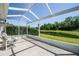 Enclosed patio overlooking a well-manicured lawn and pond with chairs to sit and enjoy the view at 7233 Mystic Brook Way, Davenport, FL 33896