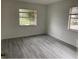 A bright bedroom is shown with modern gray flooring and two large windows at 7604 Forest City Rd # 11, Orlando, FL 32810