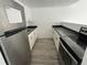 Galley kitchen featuring stainless steel refrigerator, light wood floors, white cabinets, and black countertops at 7604 Forest City Rd # 11, Orlando, FL 32810