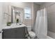 Well-lit bathroom featuring a shower/tub with white curtain, toilet, window, and gray vanity at 772 Driving Range Ct, Kissimmee, FL 34747