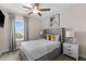 Well-lit bedroom featuring a ceiling fan, large window, gray headboard, and modern nightstands with lamps at 772 Driving Range Ct, Kissimmee, FL 34747
