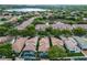 Expansive aerial view of a neighborhood with tile roofs, mature trees, and a serene lake in the background at 8333 Via Verona, Orlando, FL 32836
